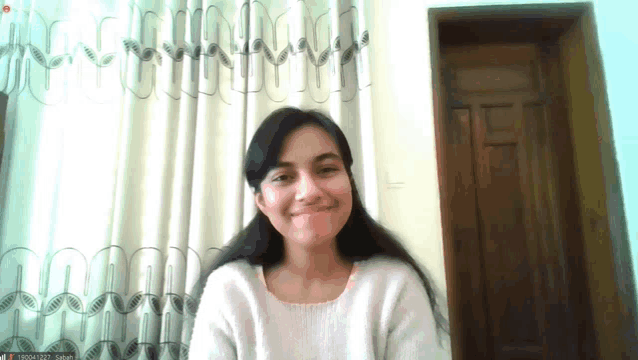a woman in a white sweater is smiling and looking at the camera