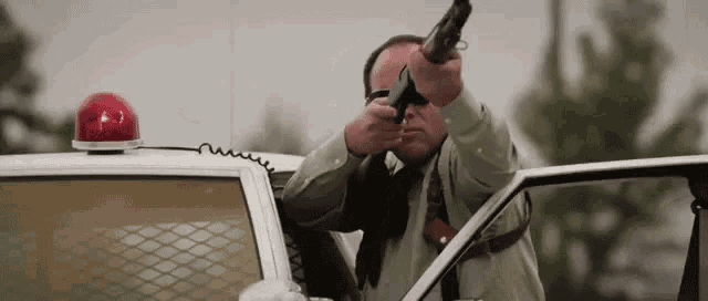 a police officer is pointing a shotgun out of a police car