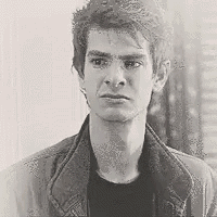 a black and white photo of a man in a denim jacket looking at the camera .