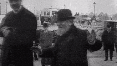 a black and white photo of a man in a hat and coat