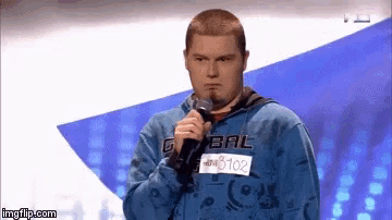 a man in a blue bal sweatshirt is holding a microphone in front of him