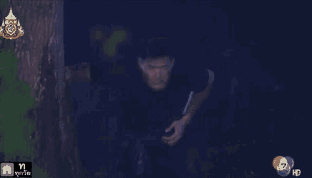 a man in a black shirt is standing in the dark with a hd logo in the upper right corner