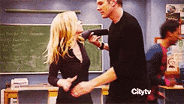 a man and a woman are dancing in a classroom with a city tv logo in the corner
