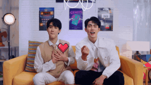 two men are sitting on a couch with posters on the wall including one that says ' survival '
