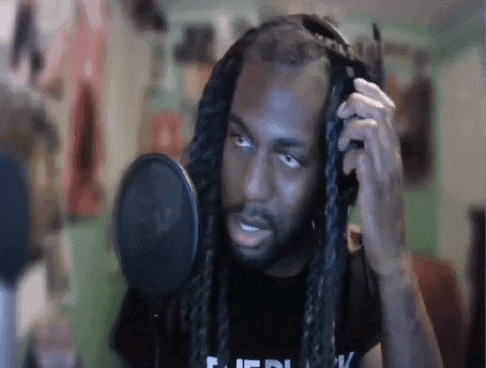 a man with long dreadlocks is standing in front of a microphone .