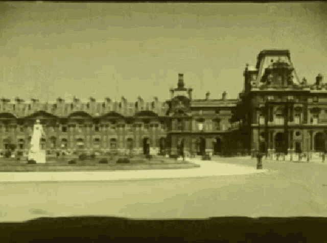 a black and white photo of a large building with a statue in the foreground