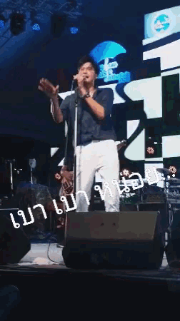 a man singing into a microphone on a stage with a sign in the background that says ' umbrella '