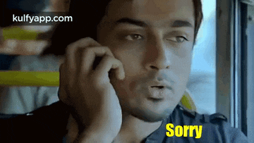 a man is talking on a cell phone and the word sorry is on his face .