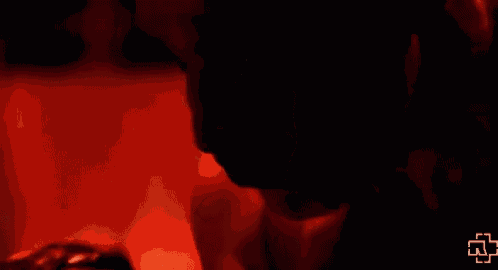a man in a black coat is standing in front of a room full of fire .