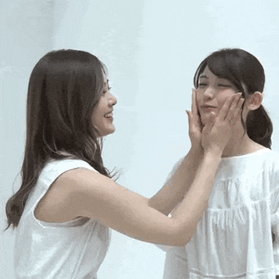 two women are touching each other 's faces with their hands .
