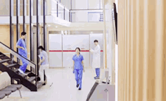 a group of nurses are walking down stairs in a hospital hallway .