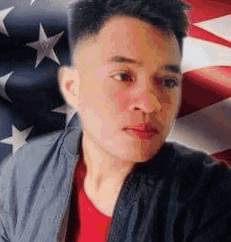 a man is taking a selfie in front of a large american flag .