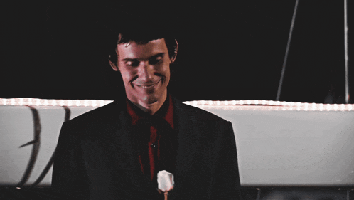a man in a suit and red shirt is smiling with his eyes closed