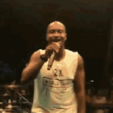 a man is singing into a microphone wearing a 2x shirt