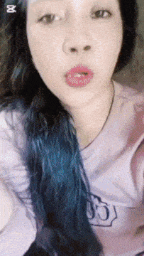a woman with blue hair is wearing a purple shirt with the letter g on it