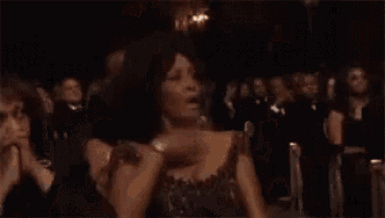 a blurry picture of a woman dancing in a dark room with a chandelier in the background .