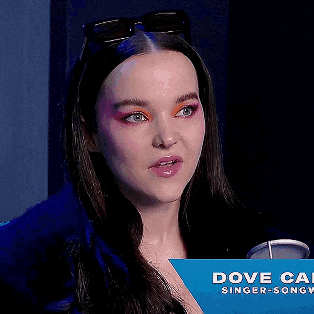 a close up of a woman behind a sign that says dove cal singer-songw