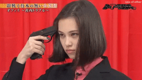 a woman is holding a gun to her head in front of a red curtain ..