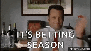 a man in a suit and tie is holding a glass of wine and saying `` it 's betting season ''