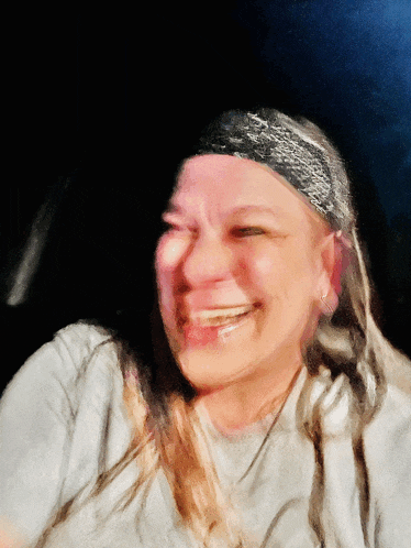 a woman wearing a headband and a gray shirt is laughing