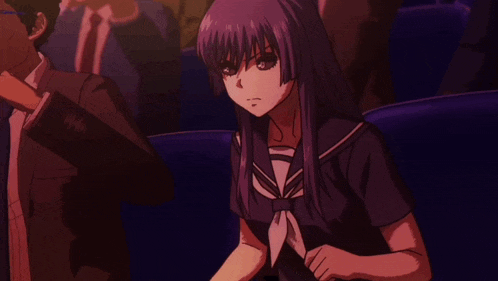 a girl with purple hair is sitting next to a man in a suit in a dark room