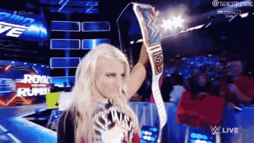 a woman in a wrestling ring holds up a championship belt with the words royal rumble in the background