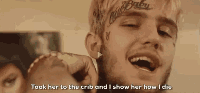 a man with a tattoo on his forehead is smiling and holding a woman 's hand .