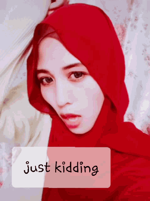 a woman wearing a red hijab with the words just kidding written below her