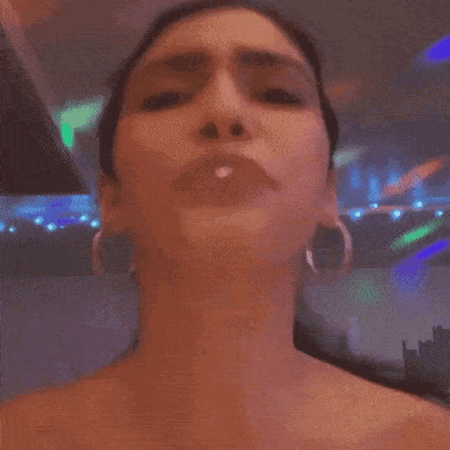 a woman wearing hoop earrings is making a face