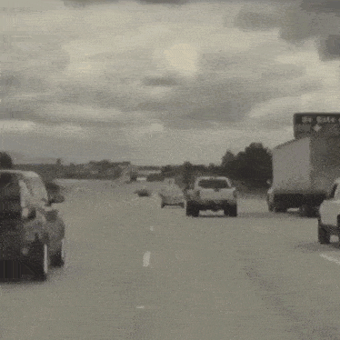 a black and white photo of a highway with cars and trucks on it