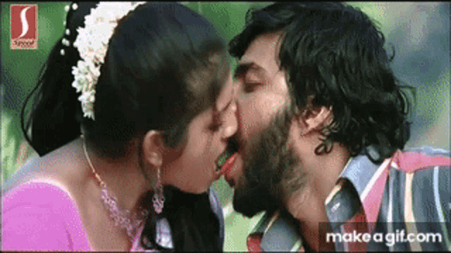 a man and a woman are kissing with a s on the bottom right