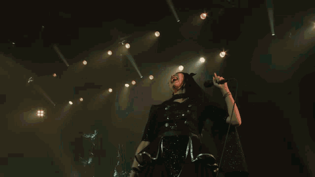 a woman with blue hair is singing into a microphone on stage