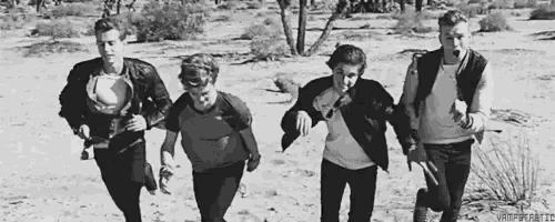 a group of young men are walking in the desert holding hands