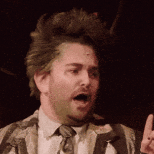 a man in a suit and tie with green hair is making a funny face