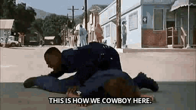 a man is laying on top of another man on the ground in a street .