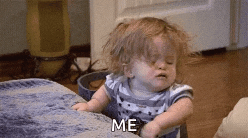 a baby girl is sitting on a couch and making a funny face while saying `` me '' .