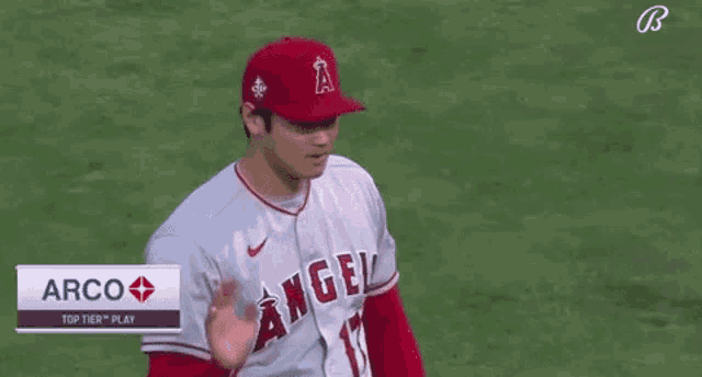 a baseball player wearing a red hat is standing on a field with his hands on his chest .