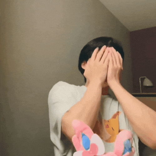 a man is covering his face with his hands while holding a stuffed animal ..