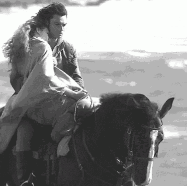 a man and woman are riding a horse on the beach .