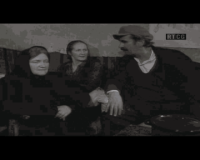 a man and two women are sitting in front of a sign that says rtcg on it