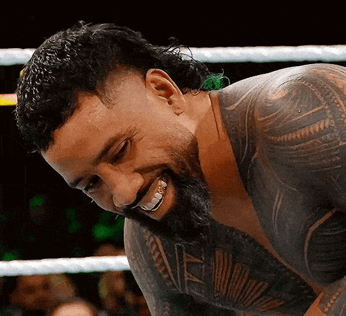 a man with a beard and tattoos is smiling in a ring .