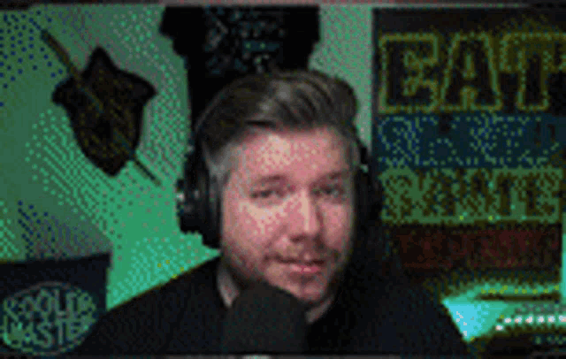 a man wearing headphones is talking into a microphone in front of a sign that says " eat "