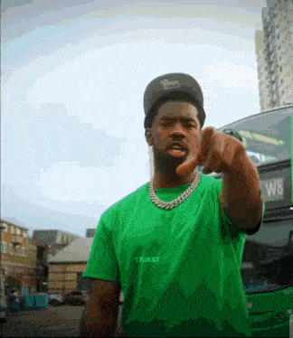 a man wearing a green shirt that says 17jxst points at the camera