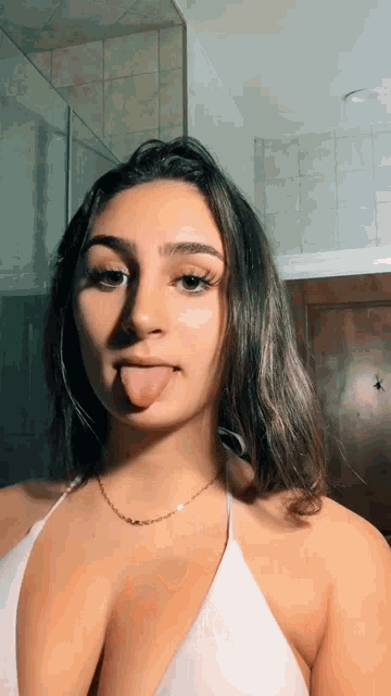 a young woman is sticking her tongue out in front of a mirror .