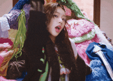 a woman is sitting on a pile of stuffed animals