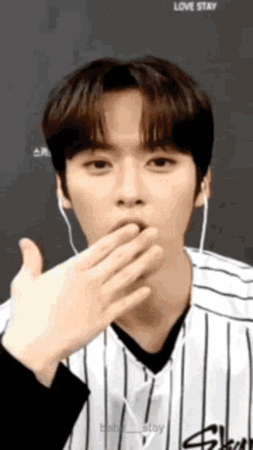 a young man in a striped shirt is blowing a kiss .
