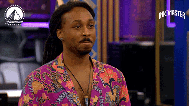 a man in a purple floral shirt is standing in front of a paramount network logo