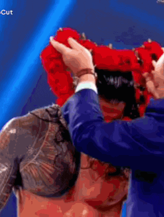 a man in a suit is putting a red crown on another man