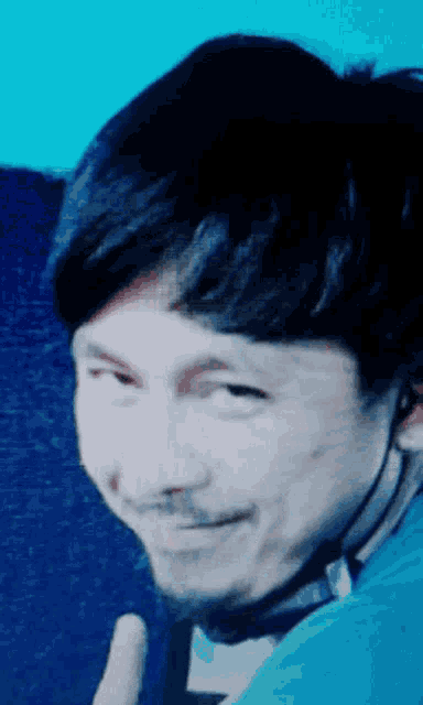 a close up of a man 's face with a blue shirt on