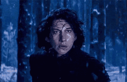 a man in a black jacket is standing in a snowy forest .